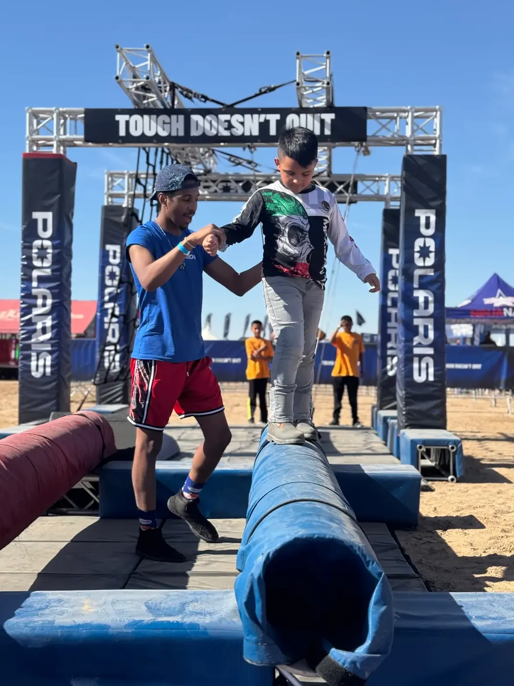 Staff member helping a child across a balance obstacle