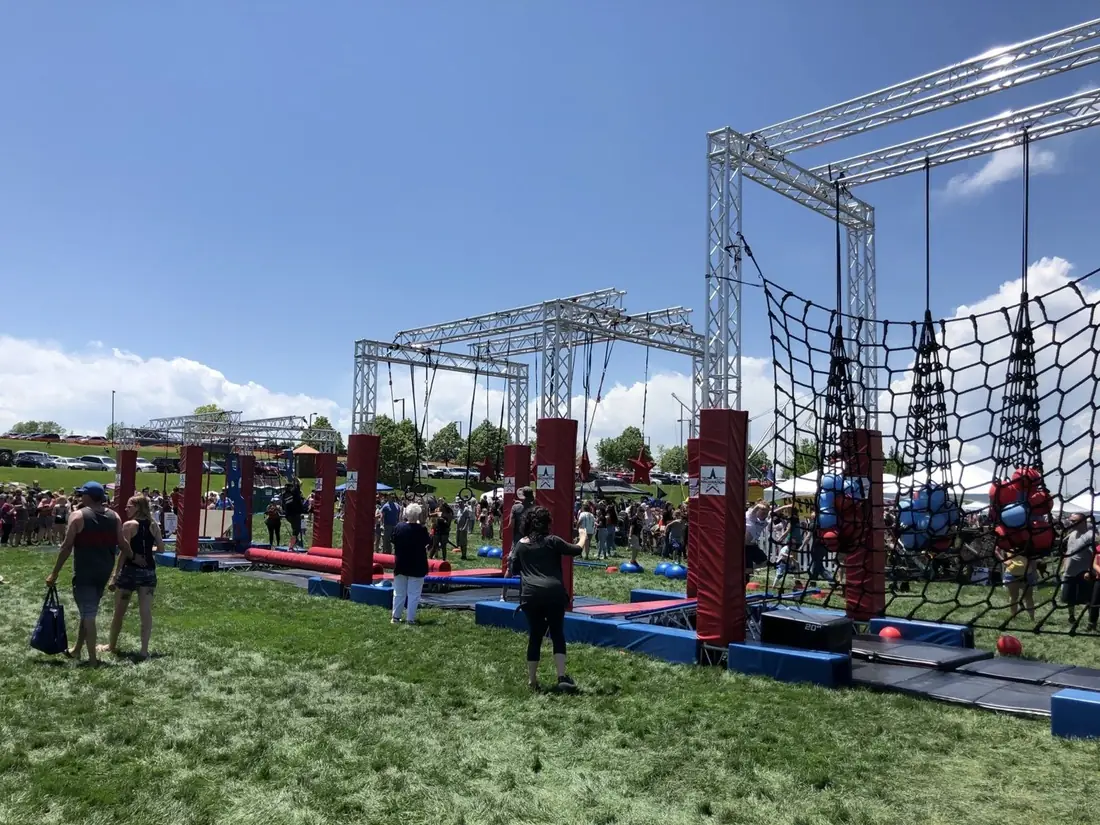 Mobile truss ninja course with cargo nets and hanging obstacles at an outdoor event